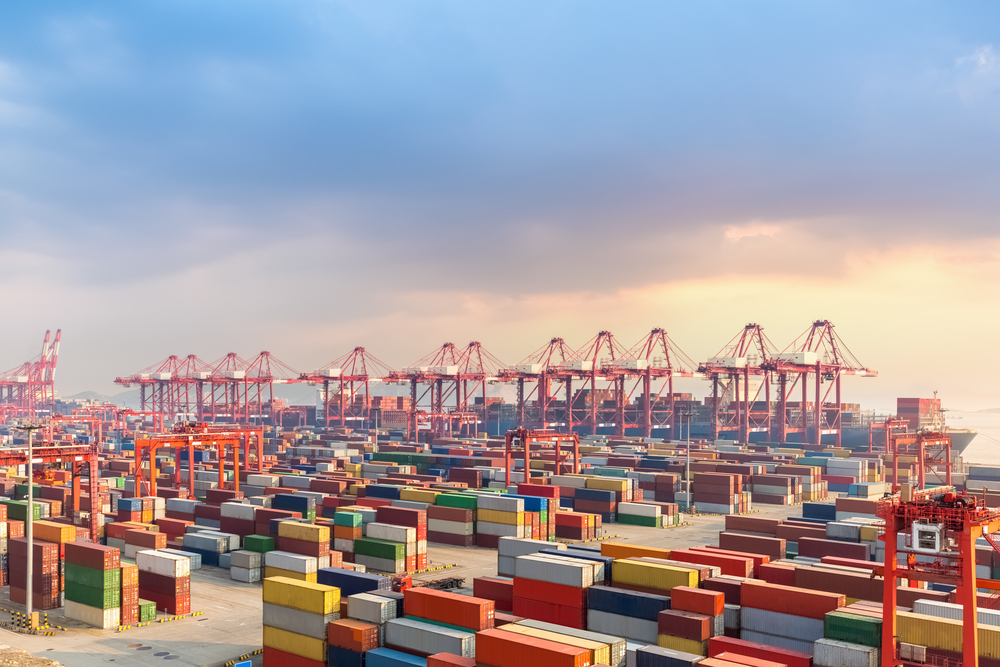 large shipping containers at a port being loaded on a ship for international freight shipping companies