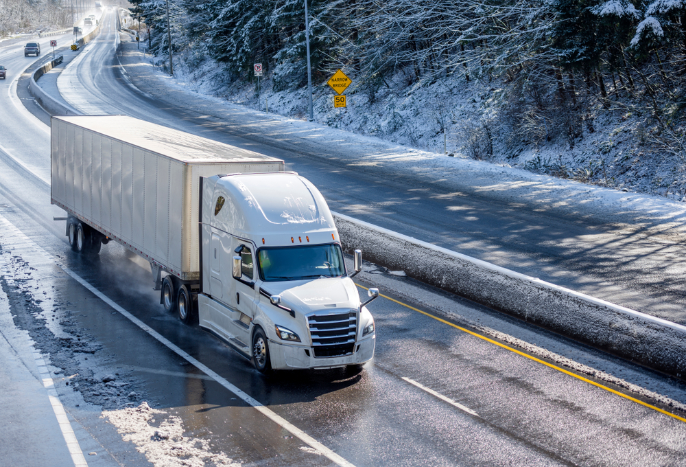 big rig driving through the snow for a ground freight shipping company