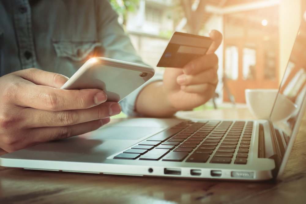 man holding credit card & phone in front of open laptop looking up 3pl warehousing and distribution